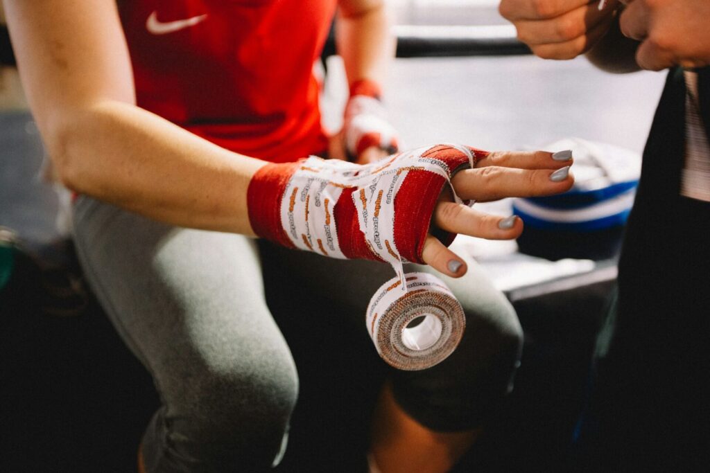 An athlete holding out her hand as a trainer wraps it with cloth and tape.