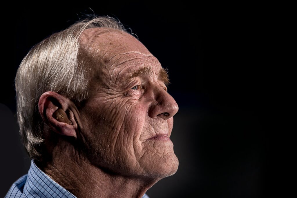 Side view of an older gentleman's face. There's a hearing aid in his ear.