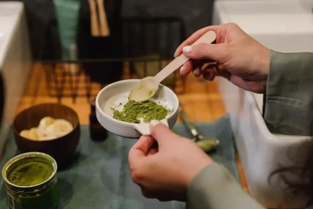 A brown powder is being mixed in a small dish with a spoon.