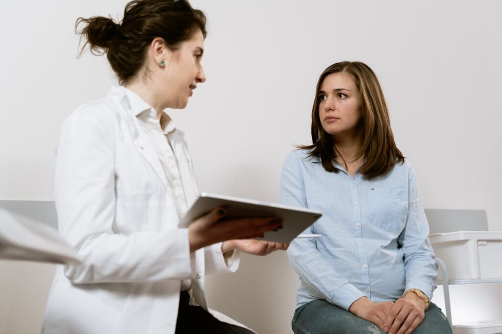 Two women sit. One is a doctor and is advising the other.