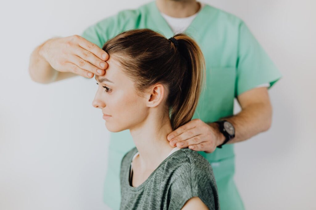 A medical professional puts his hand on a woman's forehead.