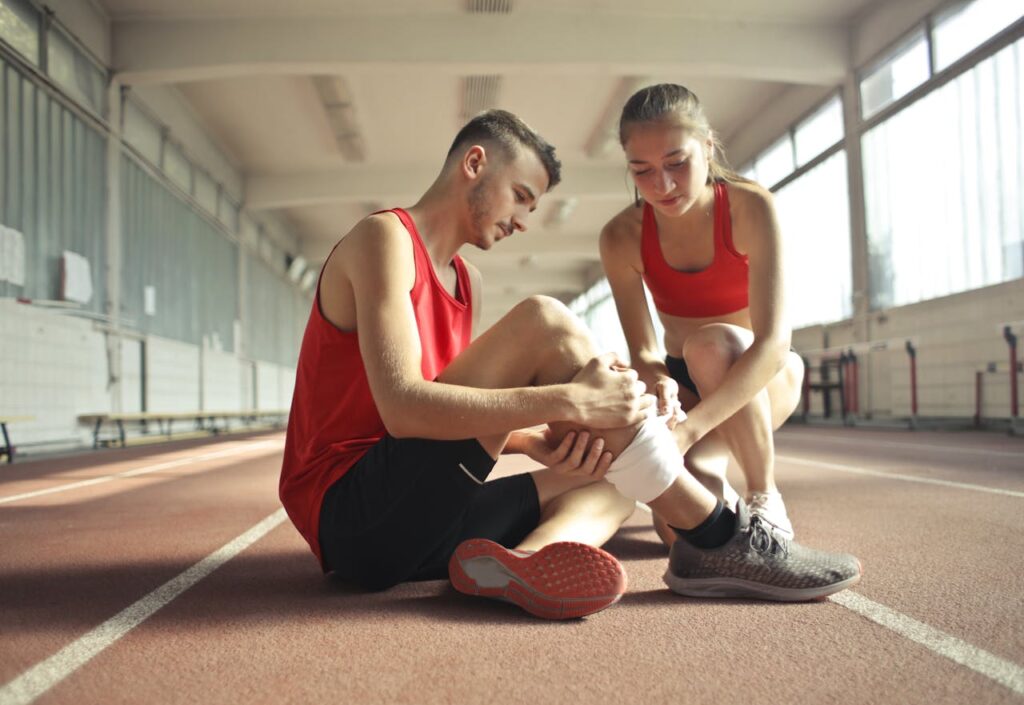 A woman wraps a bandage around a guys shin.