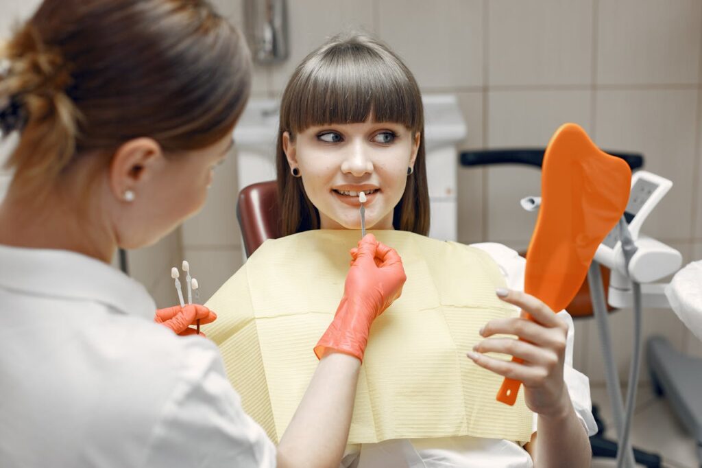 A girl sits in a dental chair as someone cleans her teeth.